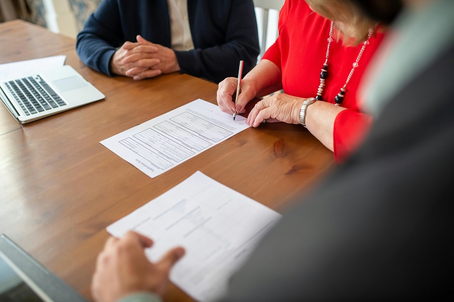 Woman Signing a will in the Presence of Lawyers