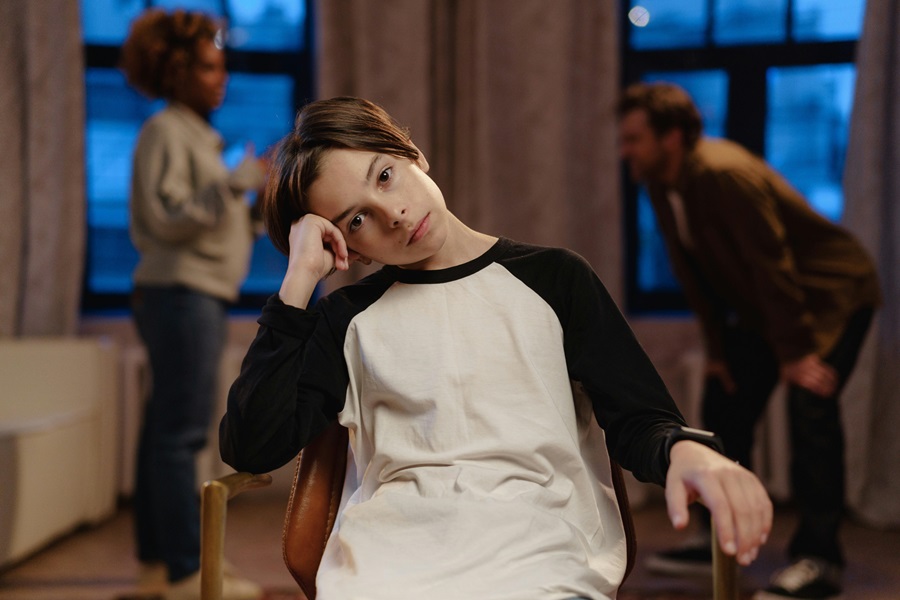 Child appearing withdrawn while parents argue in the background, illustrating parental alienation and emotional impact on a child in a family dispute.
