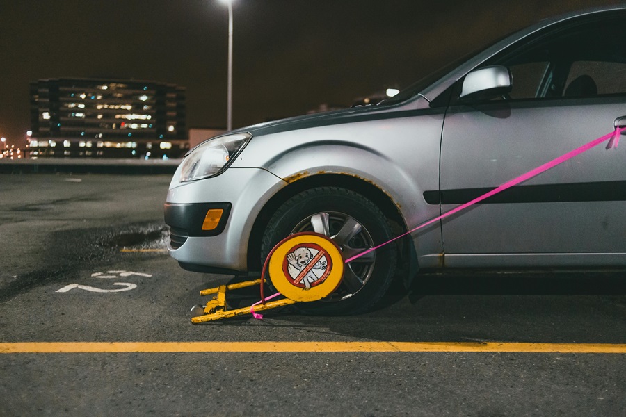 Car with wheel clamp in a parking area