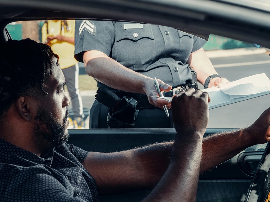 Driver signing police document during roadside stop after car seizure