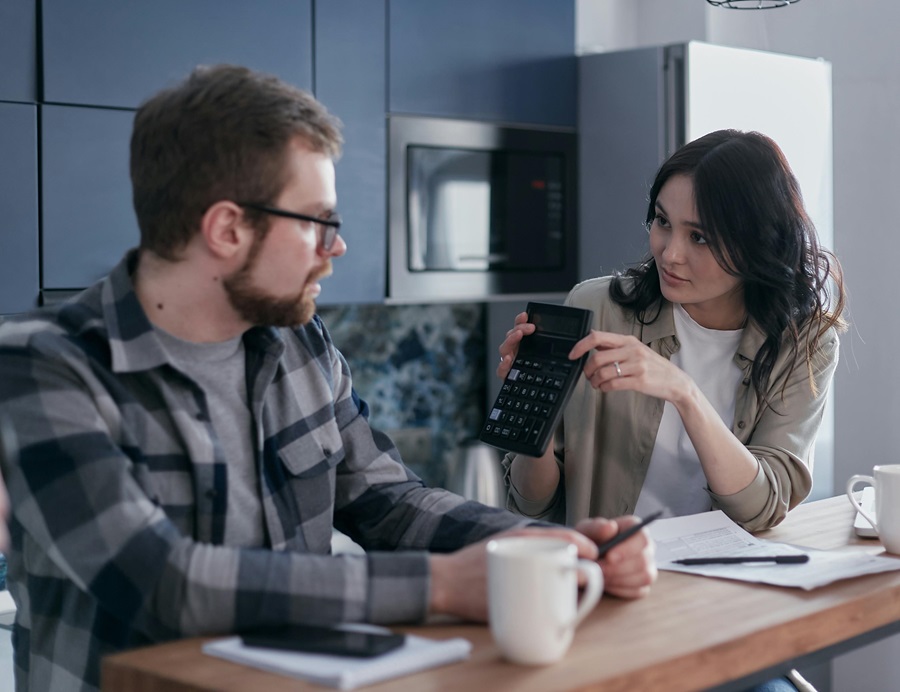 Couple reviewing expenses with a calculator and documents at home