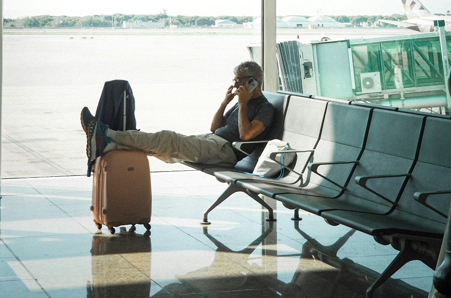 man talking on the phone in the airport waiting room for travel insurance dispute