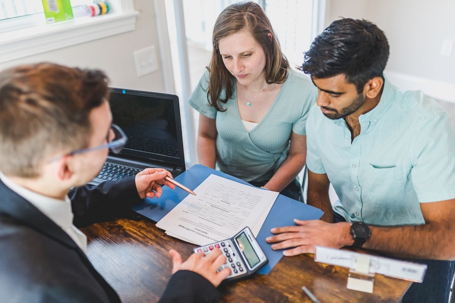 Two couples signing a property transfer contract with a UK conveyancing solicitor during a home buying process.