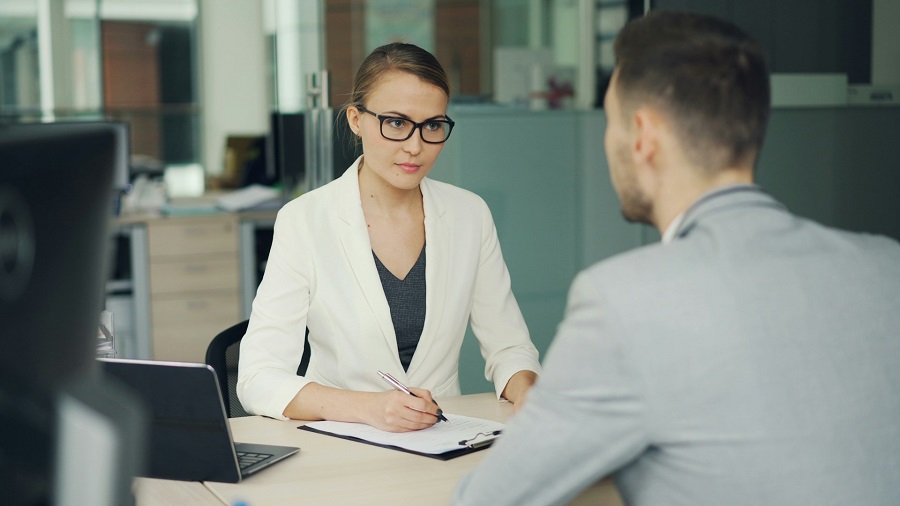A woman with glasses is questioning a man in the office.