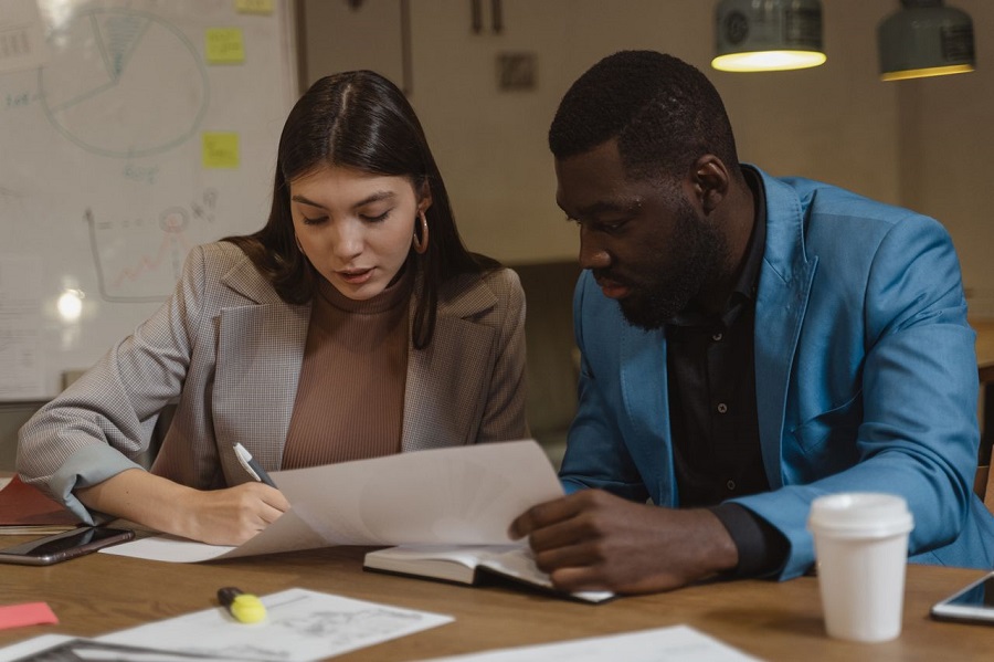 Two colleagues collaborating on documents at a desk